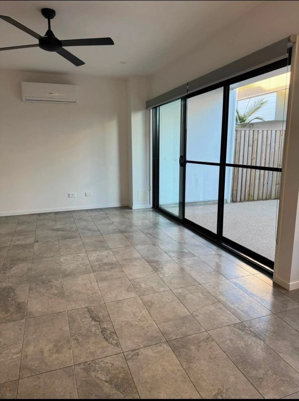 Modern empty room with tiled floor and sliding glass doors.