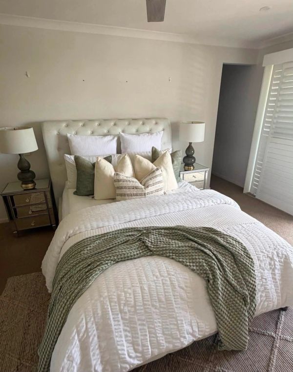 Cozy bedroom with neutral tones and layered pillows.