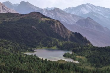 Serene mountain lake surrounded by lush forests and towering peaks.