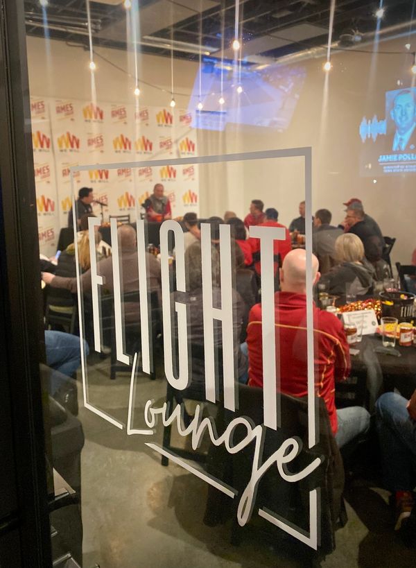 People gathered in a room labeled Flight Lounge for an event or meeting.