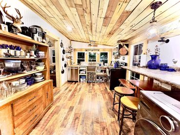 Rustic kitchen with wood ceiling, open shelving, and cozy decor.
