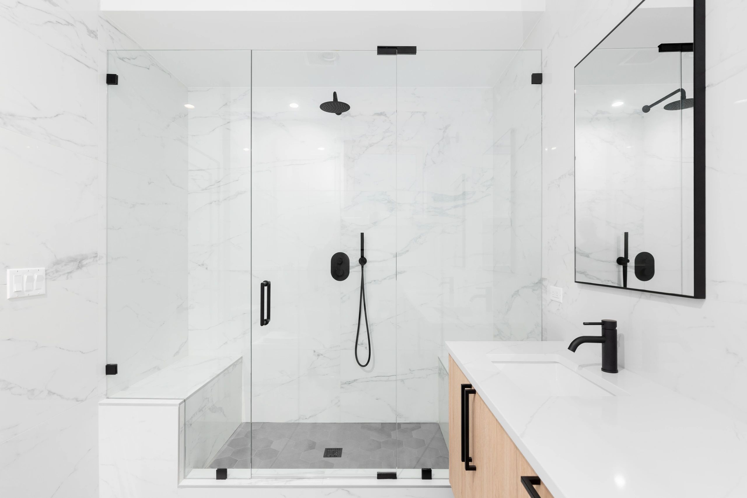 porcelain white gray tile shower with bench and gray hexagon floor 