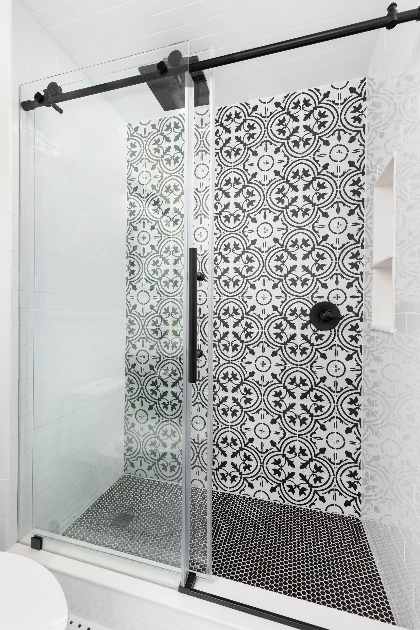 white subway tile shower with black white pattern tile feature penny round mosaic floor and niche