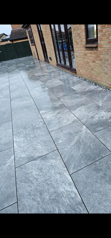 Wet gray stone tiles laid in a neat pattern along a brick house.