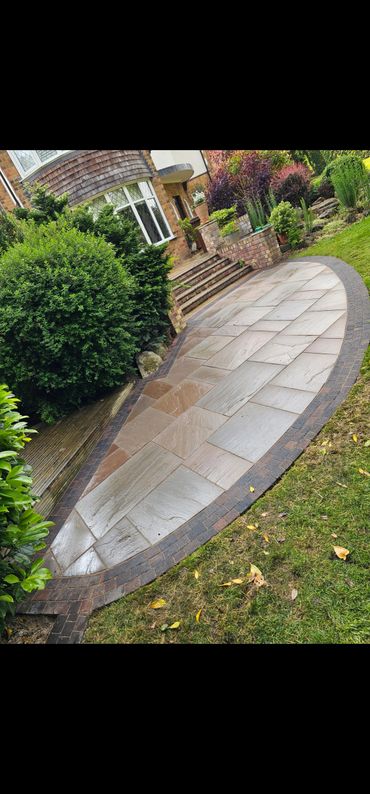 Wet stone patio with brick border in a garden setting.