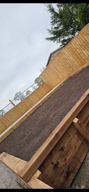 Freshly prepared garden bed with wooden borders and tilled soil, surrounded by wooden fencing.