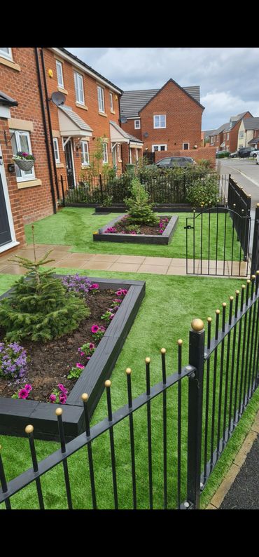 Neatly landscaped front yard with artificial grass and flower beds in a suburban neighborhood.