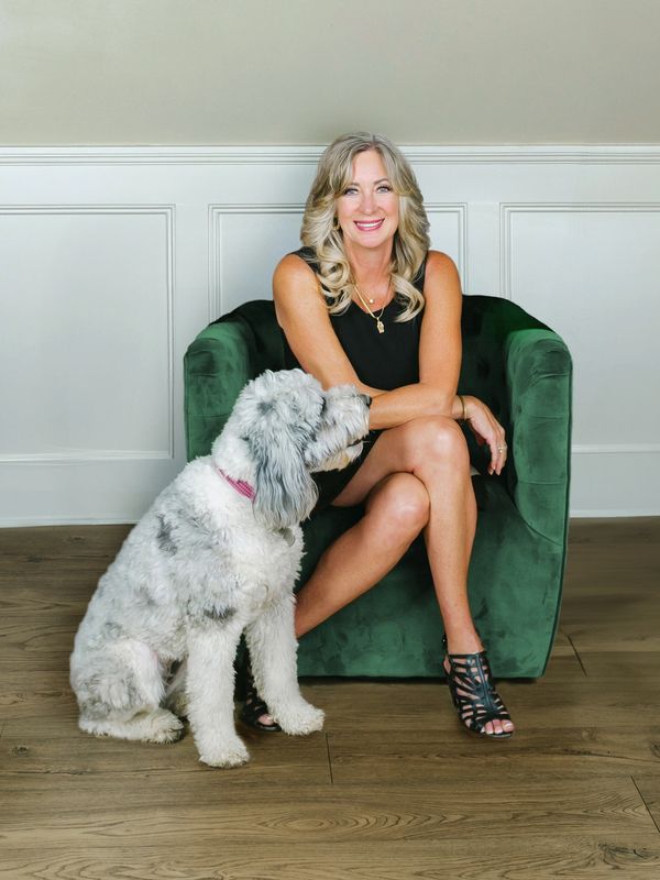 Woman sitting on green chair with a large fluffy dog.