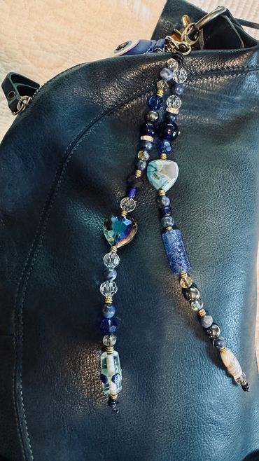 Close-up of decorative beaded accessory on black leather bag.