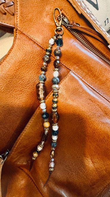 Beaded charm hanging from a brown leather bag.