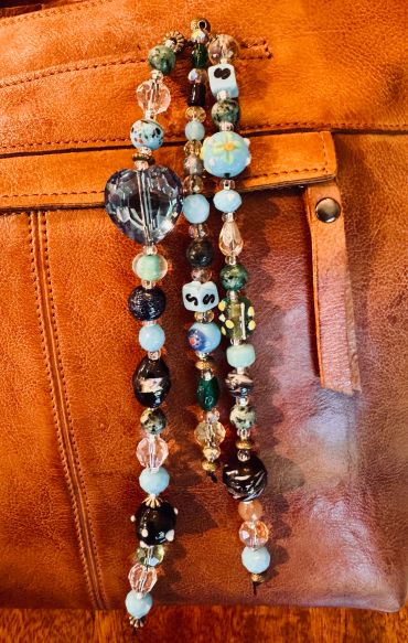 Colorful beaded necklaces on a leather surface.