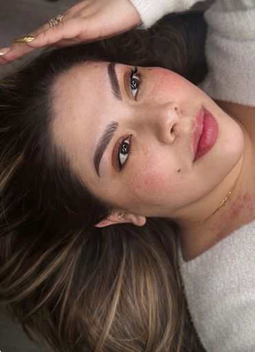 Close-up of a woman lying down, showing natural makeup and soft expression.