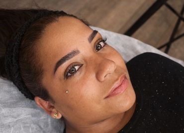 Close-up of a woman with well-groomed eyebrows and a small face piercing.