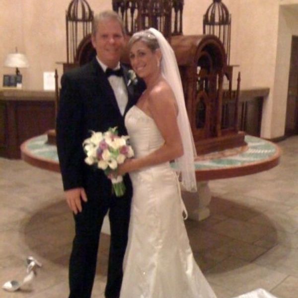 Newlywed couple posing indoors, bride holding bouquet.
