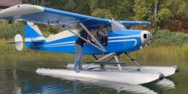 Blue seaplane on water with person exiting.
