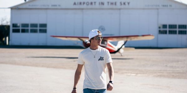 Man walking near a small airplane at an airport.