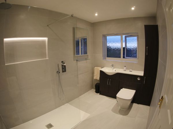 Full bathroom installation with fitted furniture and full height, tiling and low-level shower tray.