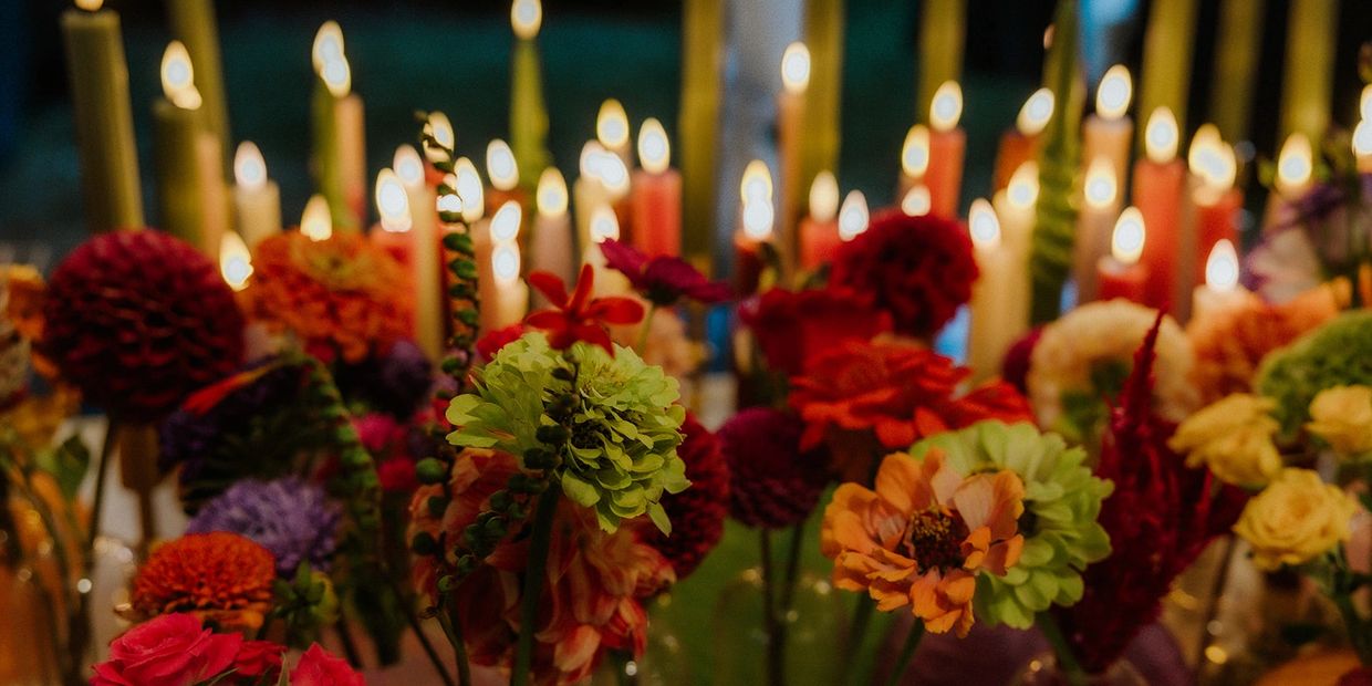 Colorful flowers in front of lit candles.