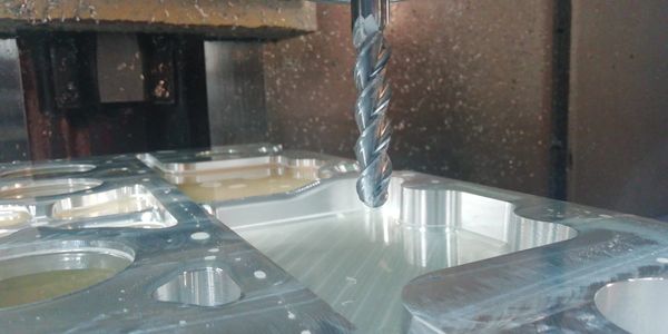 CNC milling machine cutting a metal workpiece with sparks flying.