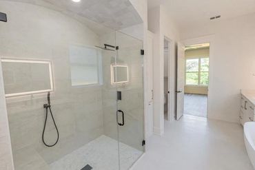 Modern bathroom with glass shower and white decor.