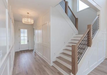 Bright modern hallway with wooden staircase and chandelier lighting.
