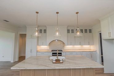 Modern kitchen with marble island and pendant lights.