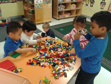 a group of children playing with lego and working together to build a structure 