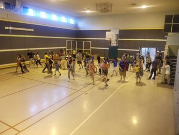 children and parents participating in a running game together in a gym