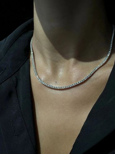 Close-up of a sparkling diamond necklace on a person wearing black.