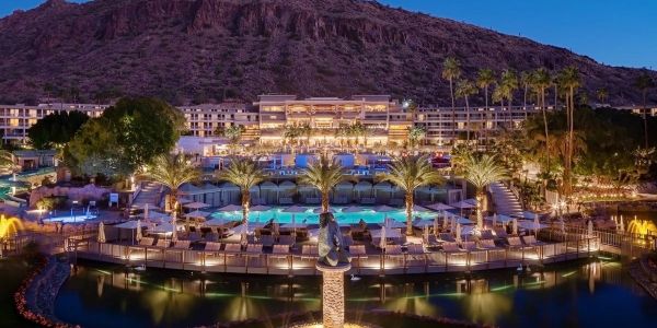 Luxury resort with pools and lit palm trees at dusk.