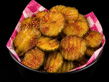 Bowl of spicy, crispy fried pickles on a checkered paper liner.