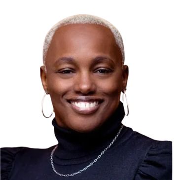 Smiling person with short blonde hair and hoop earrings in a black turtleneck.