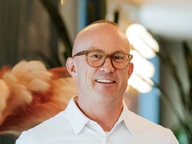Smiling man in glasses and white shirt.