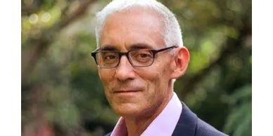 Portrait of a middle-aged man with glasses and white hair.
