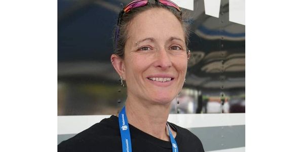 Smiling woman wearing a black shirt and blue lanyard.