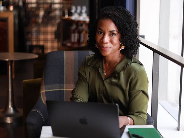 Woman working on a laptop in a cozy cafe by the window.