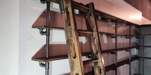 Wooden ladder leaning on industrial-style metal and wood shelving unit.