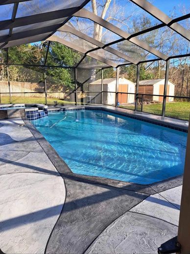 Clear swimming pool with screened enclosure in backyard.