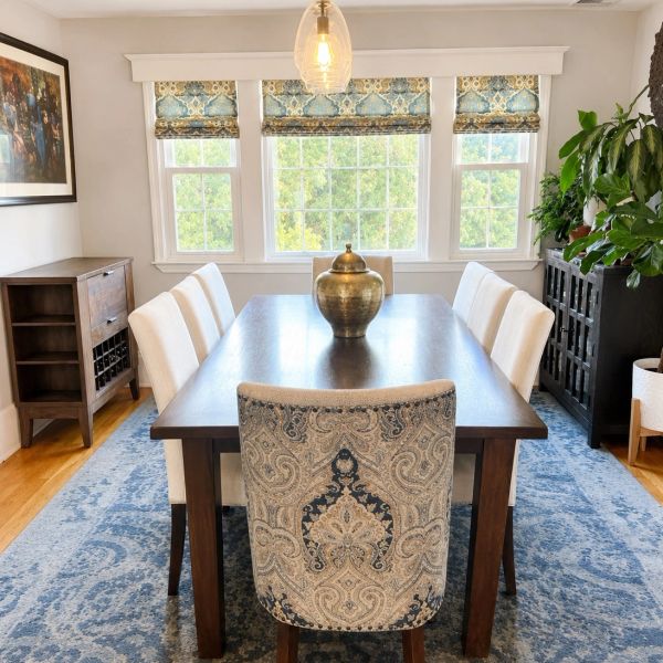 Elegant dining room with patterned chair and blue rug.