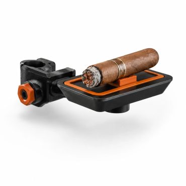 A cigar resting on a black and orange cigar holder with a clamp.