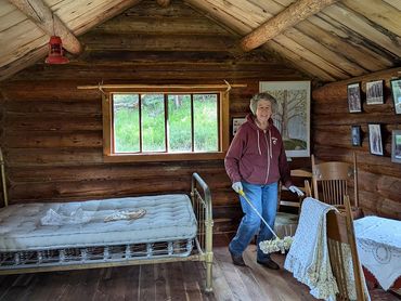 women mopping interior of log cabin