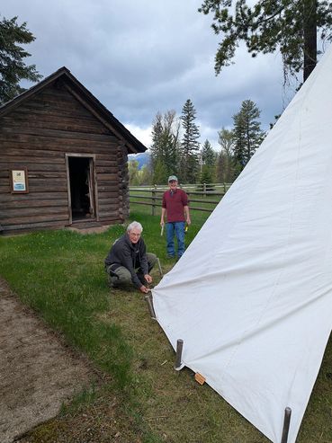 two people setting up a tipi