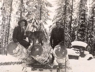 two men and dog on pile of logs