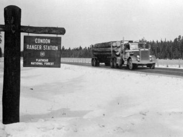 logging truck on highway, sign in foreground