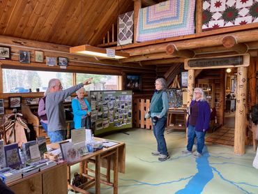 man pointing, three women standing, observing