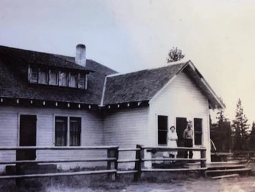 Two people standing in front of building, wood fence in foreground