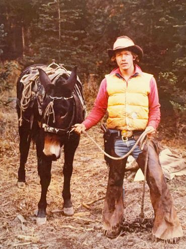 person wearing cowboy hat and chaps, with horse