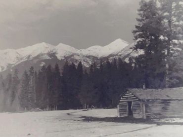 log cabin in winter, mountains in background