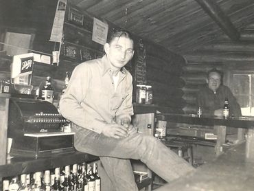 Vintage photo of young man in log cabin tavern
