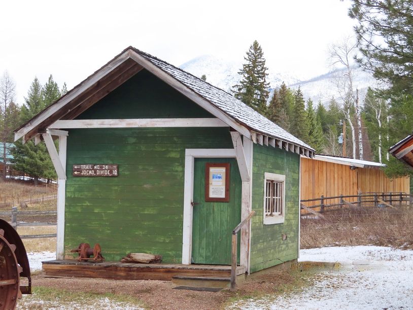 green shed with snow coverd mountain and pine trees in background